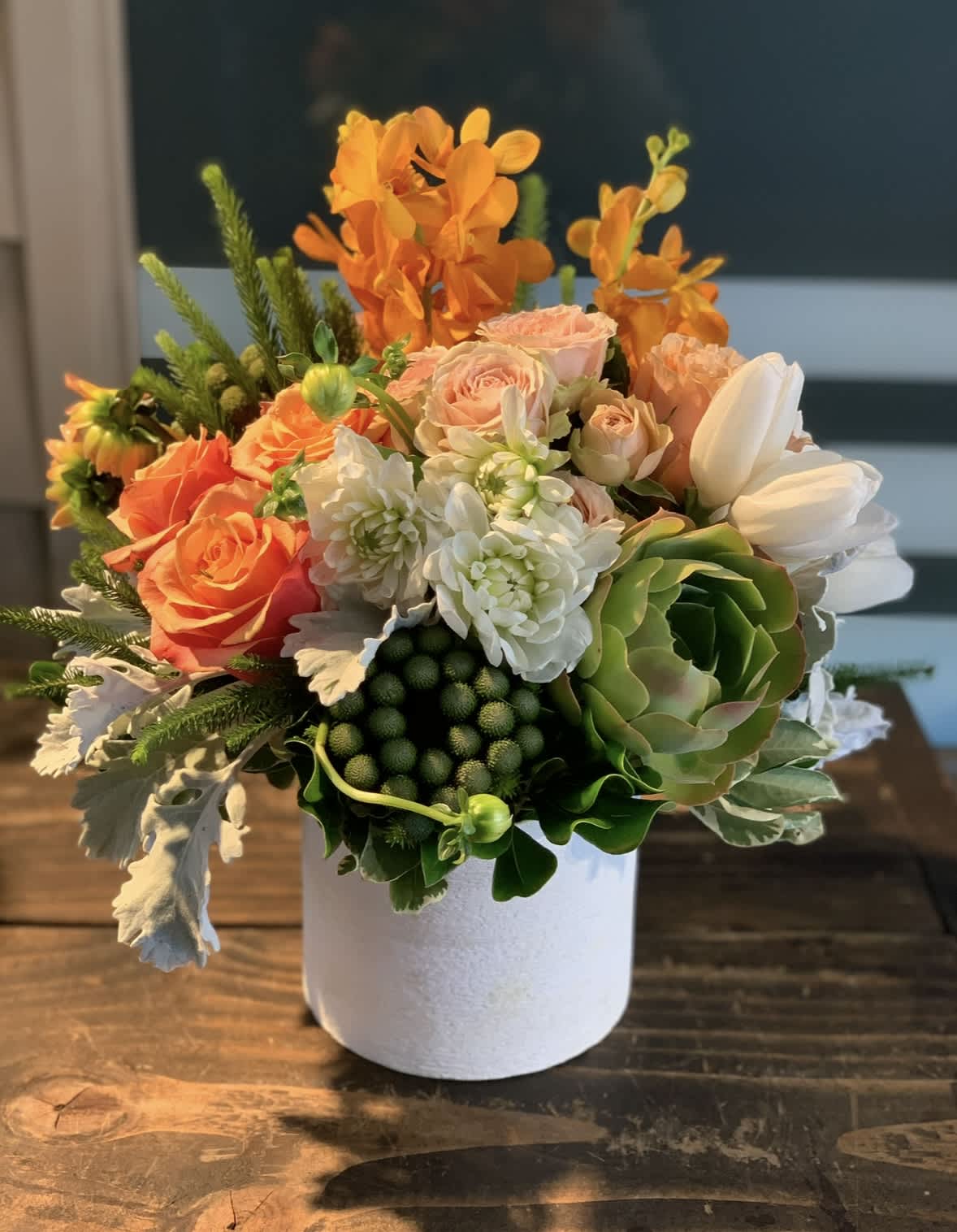 Orange and white floral arrangement in a white vase