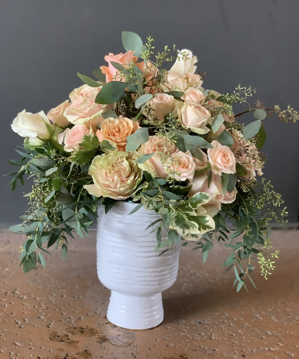 Peach and cream rose bouquet in a white vase
