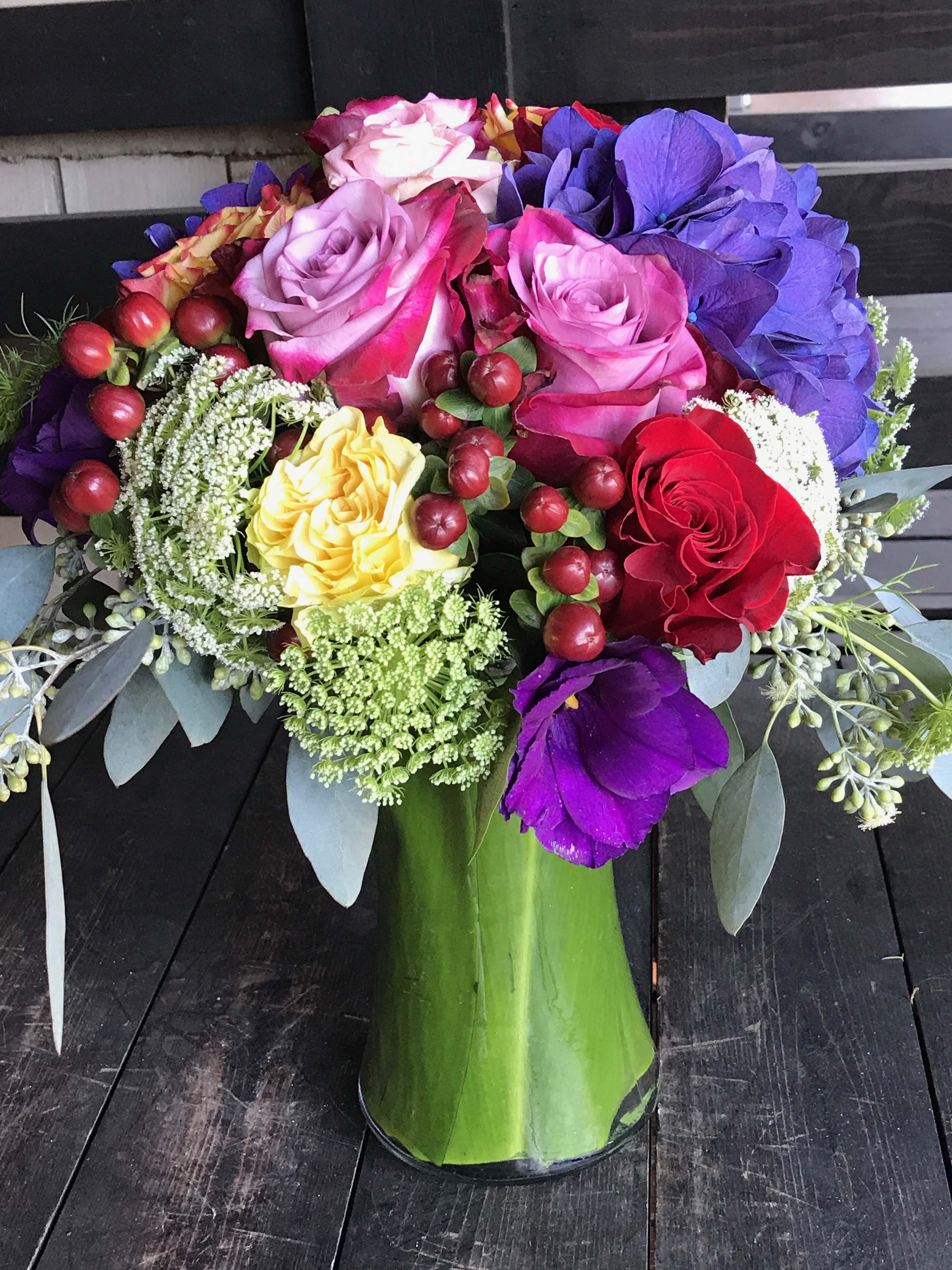 Heavenly Colors - A beautiful mix of hydrangeas, roses, lisianthus,  coffee beans and touch of queen Anne’ lace wrapped in tea leaves in a glass vase. 