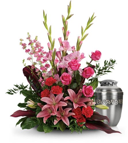 Pink lilies and roses arranged beside a silver urn