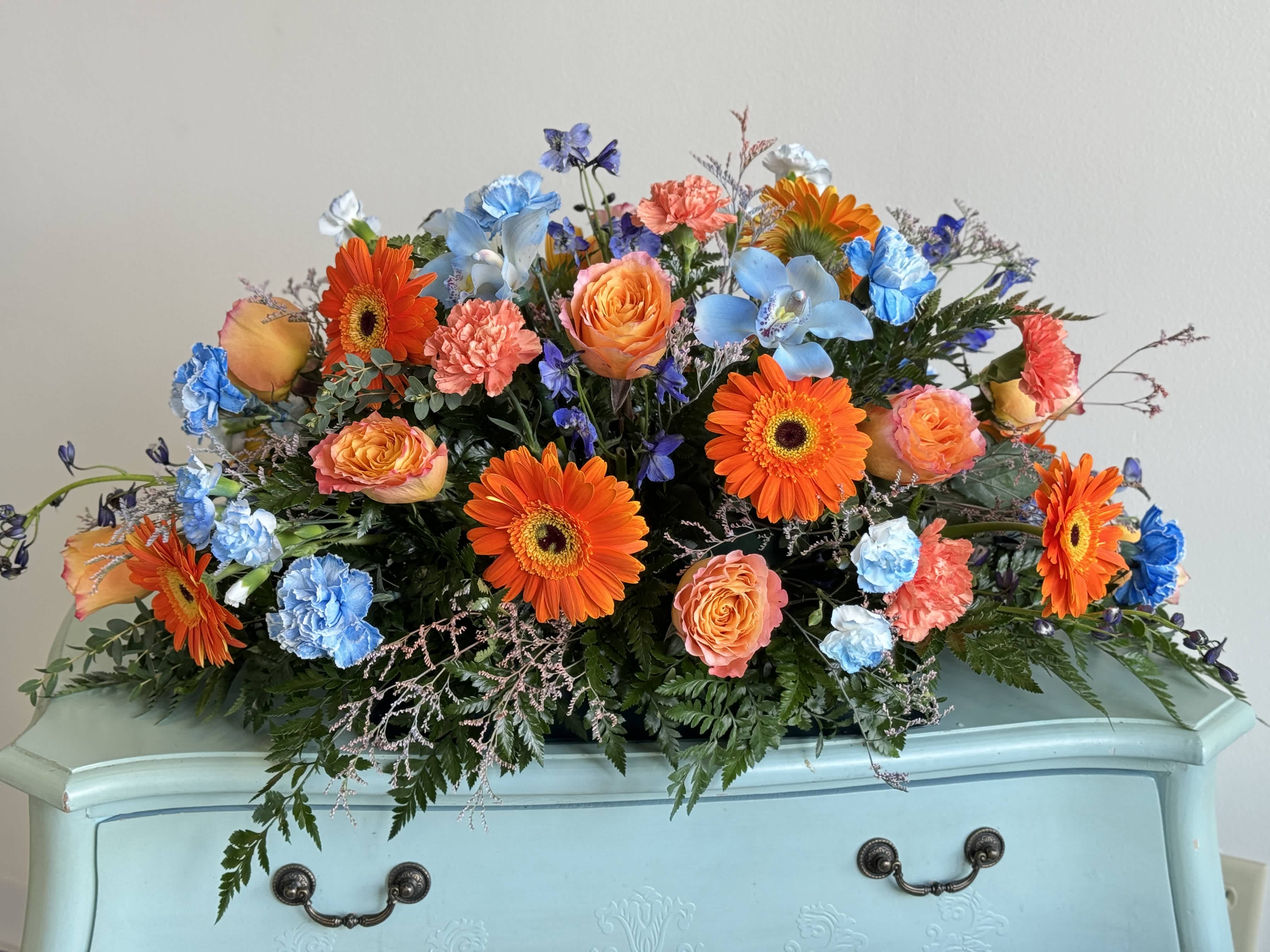 Bright mixed bouquet with orange gerberas, peach roses, and blue flowers