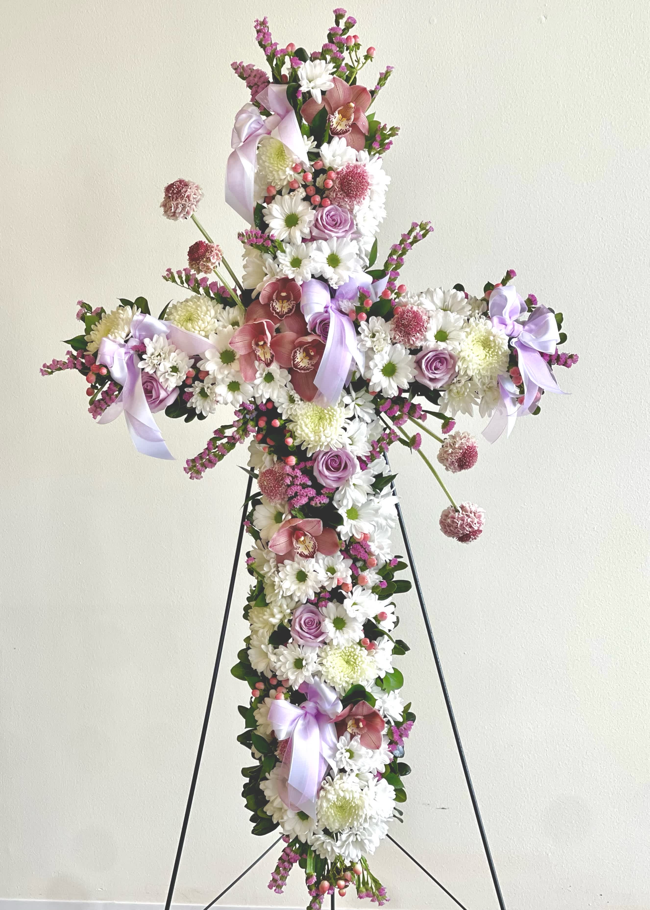Cross-shaped floral arrangement with pink and white flowers on a stand
