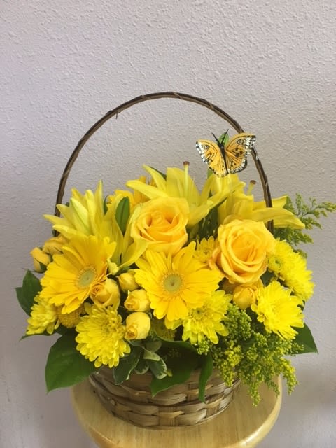 Yellow flower basket with roses, daisies, and a butterfly pick