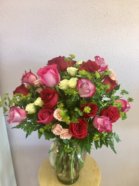 Mixed roses in pink, red, and cream arranged in a glass vase