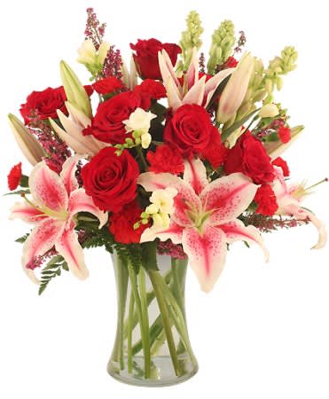 Bouquet of red roses and pink lilies in a clear glass vase