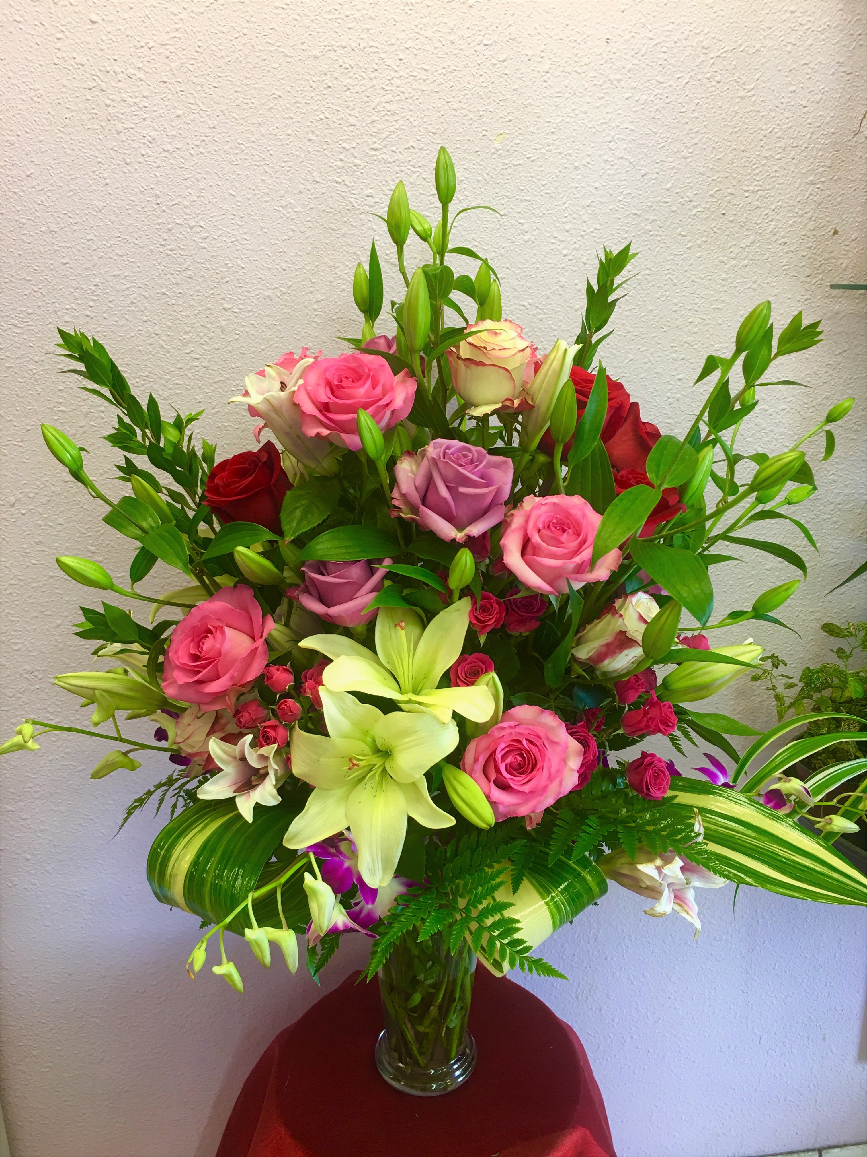 Mixed bouquet of pink and red roses with lilies in a glass vase