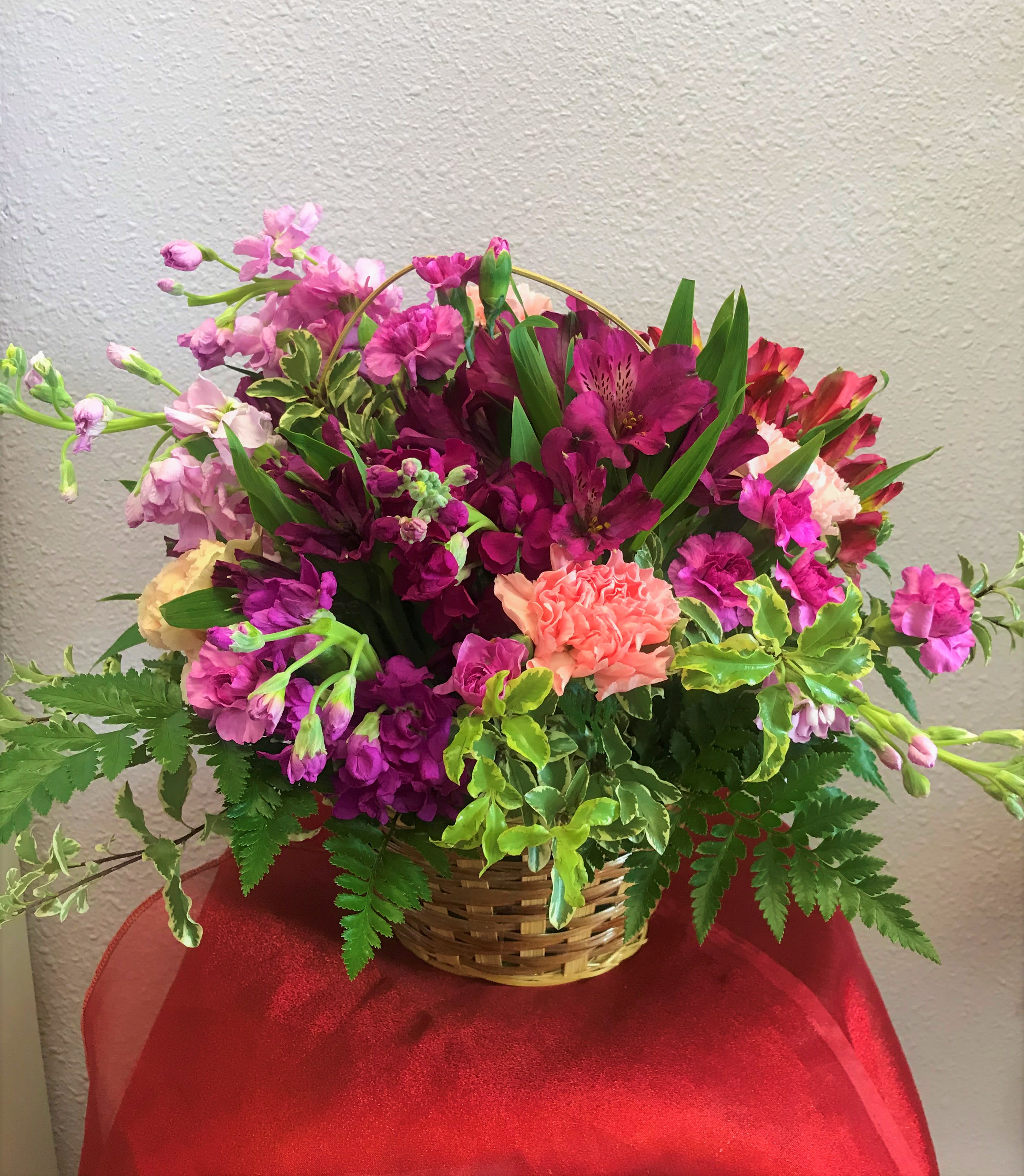 Mixed pink and purple flowers arranged in a wicker basket