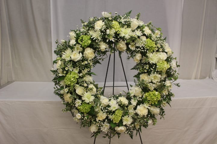 Large white and green floral wreath on a stand