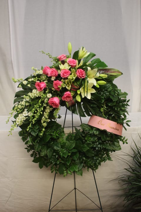 Pink roses and white lilies arranged in a large standing wreath
