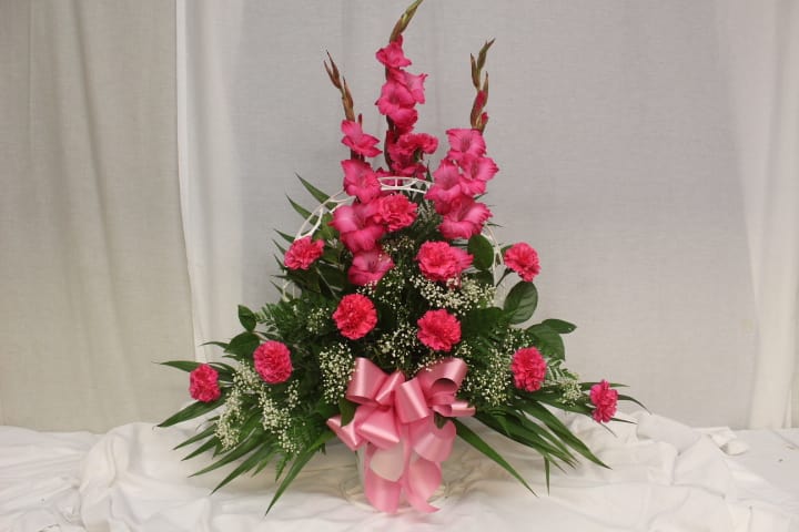 Tall pink floral arrangement with a ribbon bow in a basket