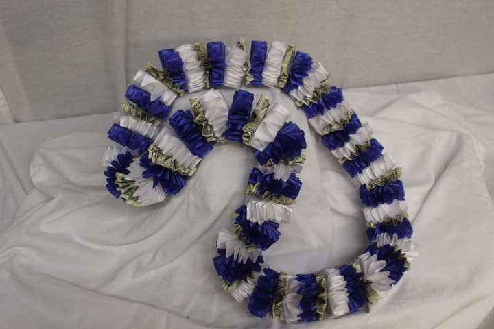 Blue, white, and money lei garlands arranged on a bed