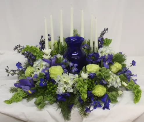 Blue and green floral centerpiece with tall white candles and a cobalt vase