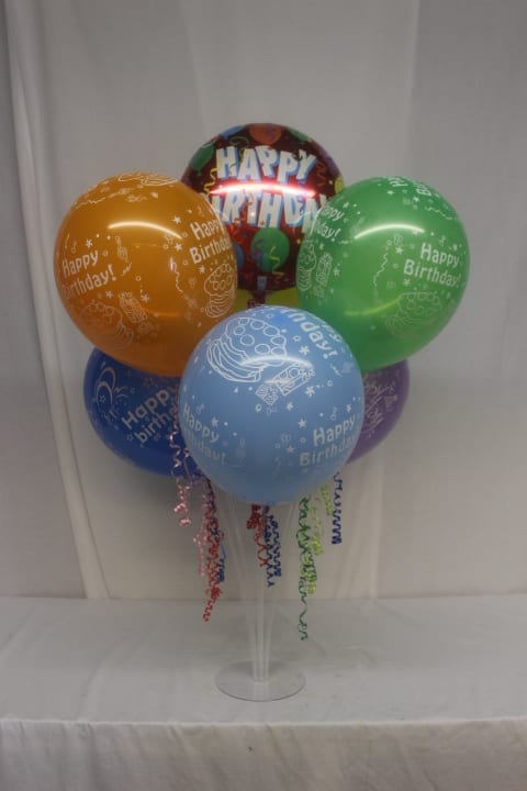 Cluster of colorful birthday balloons on a clear stand