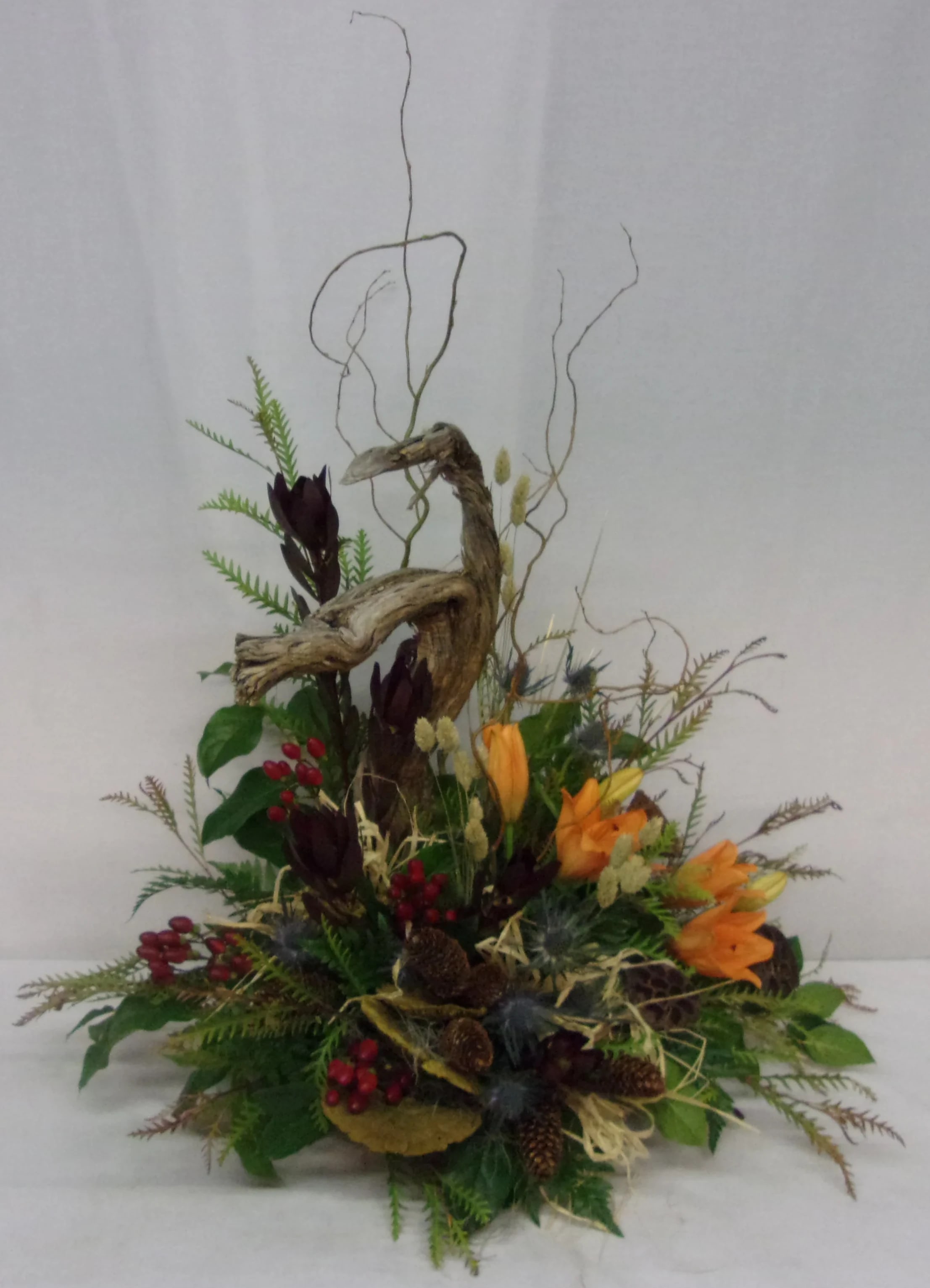 Autumn floral arrangement with orange blooms, berries, and driftwood