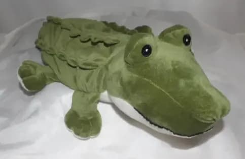 Green plush alligator toy lying on white fabric