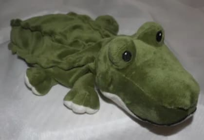 Plush green frog toy with large eyes lying on a light surface