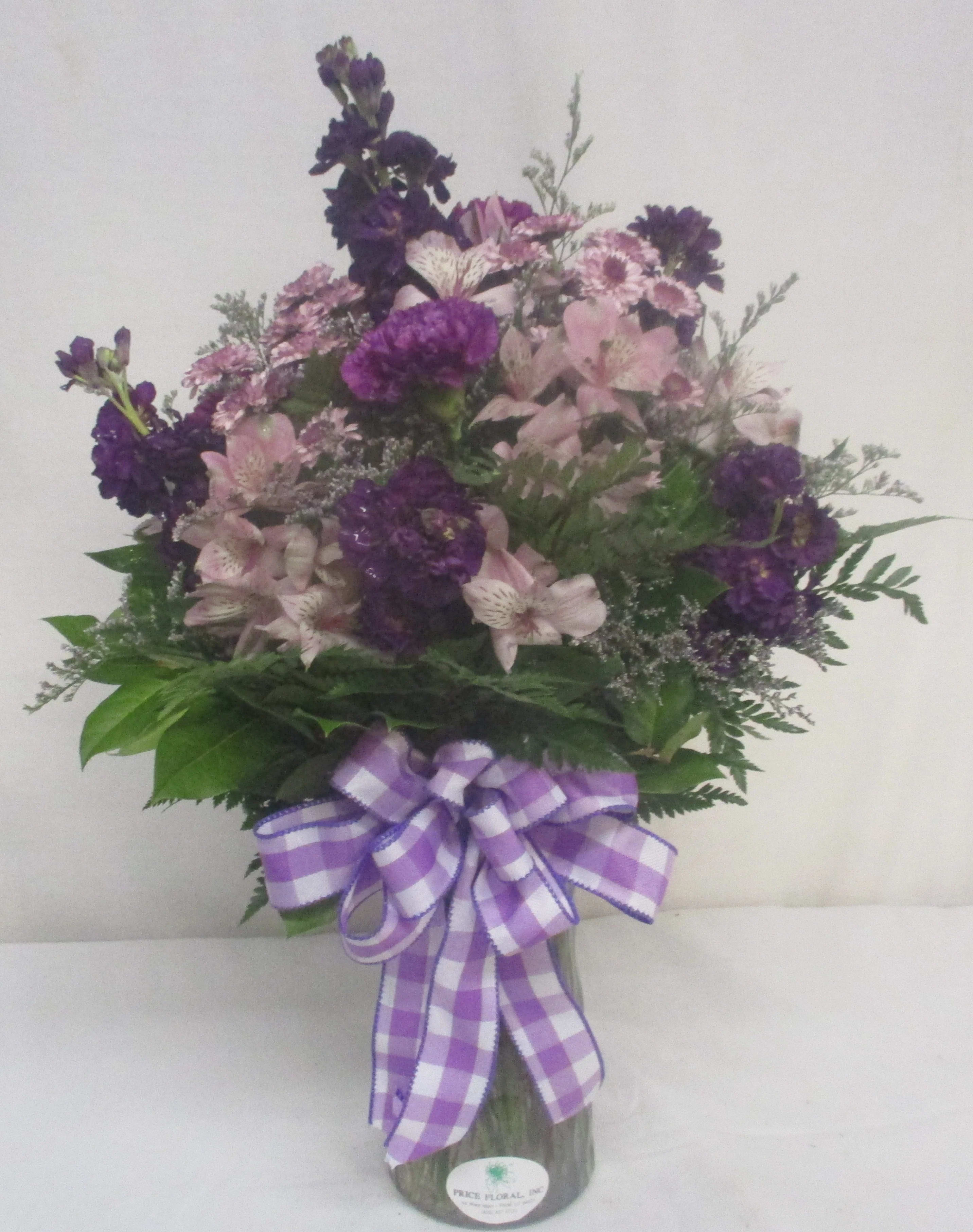Purple and pink mixed bouquet in a glass vase with a checkered ribbon