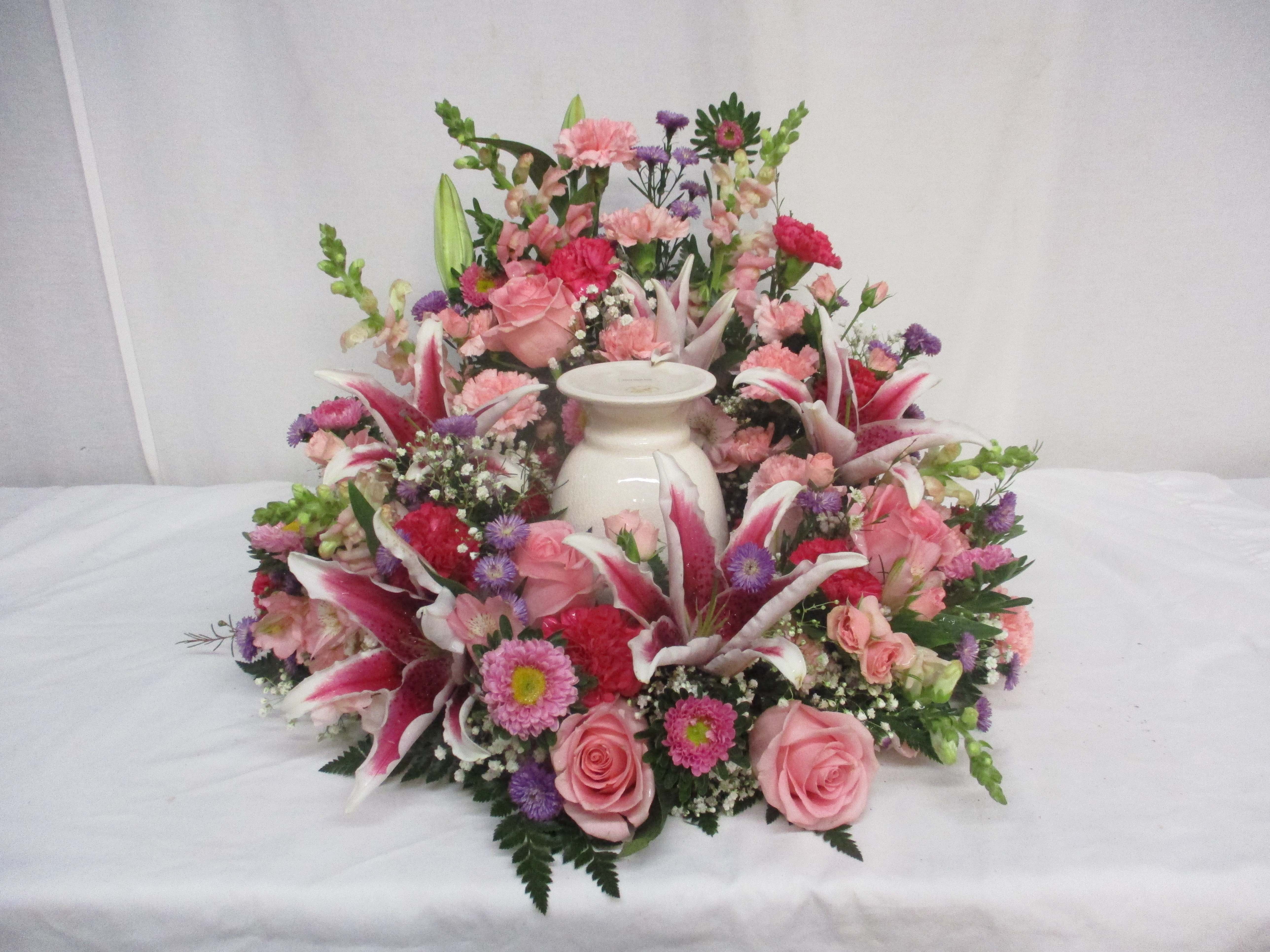 Pink and purple floral arrangement around a white urn
