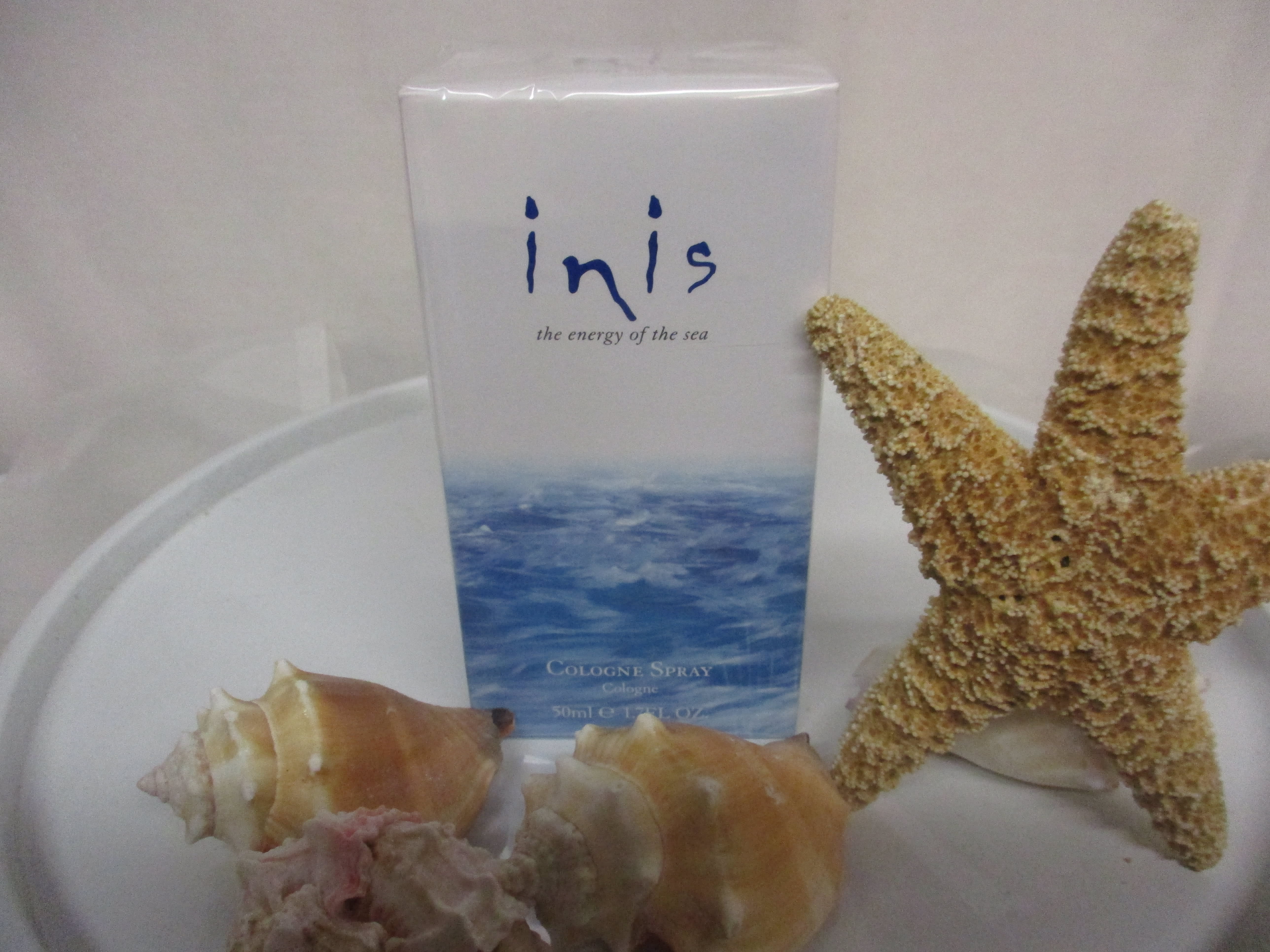 Cologne spray box with seashells and a starfish on a tray