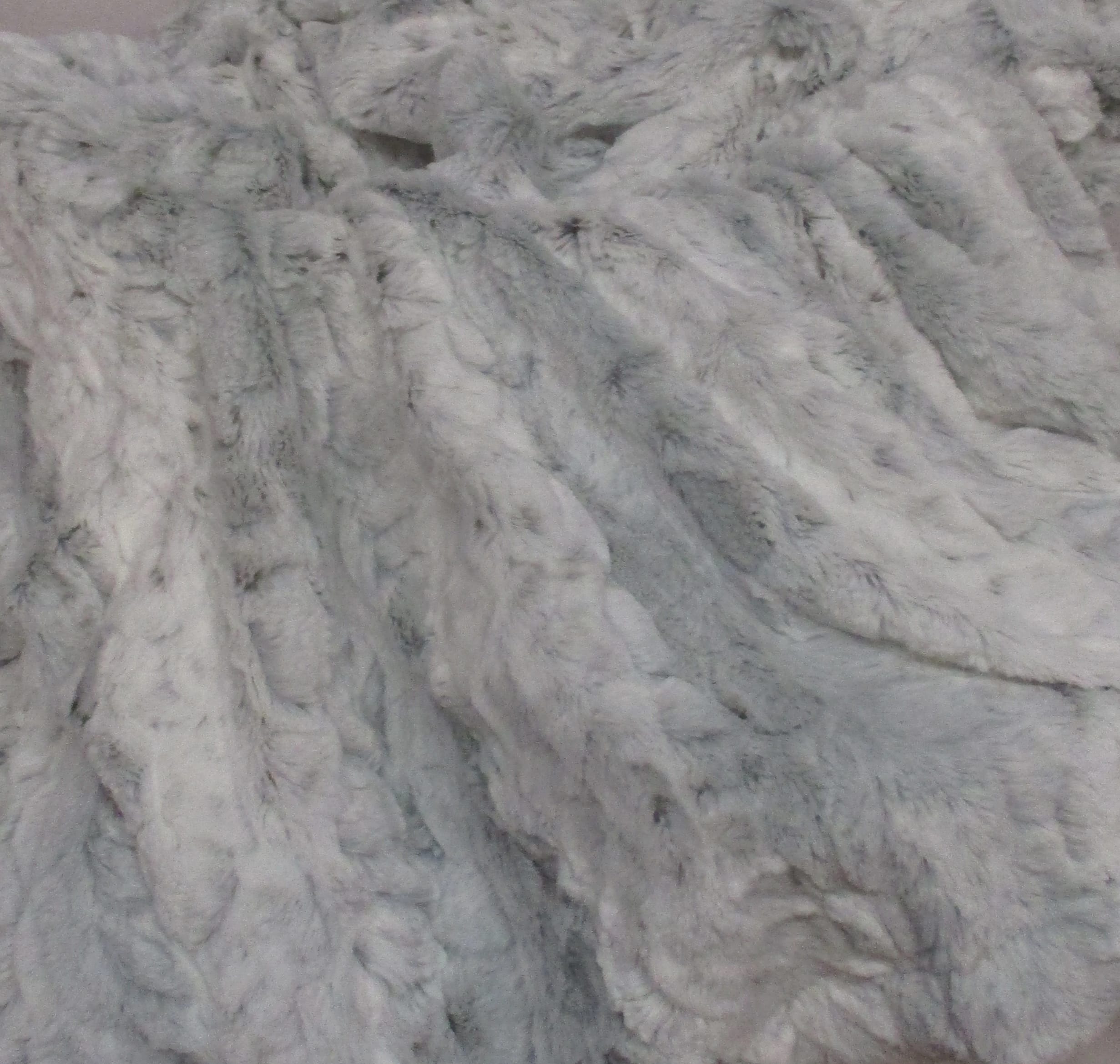 Close-up of a light gray faux fur fabric with a shaggy texture.