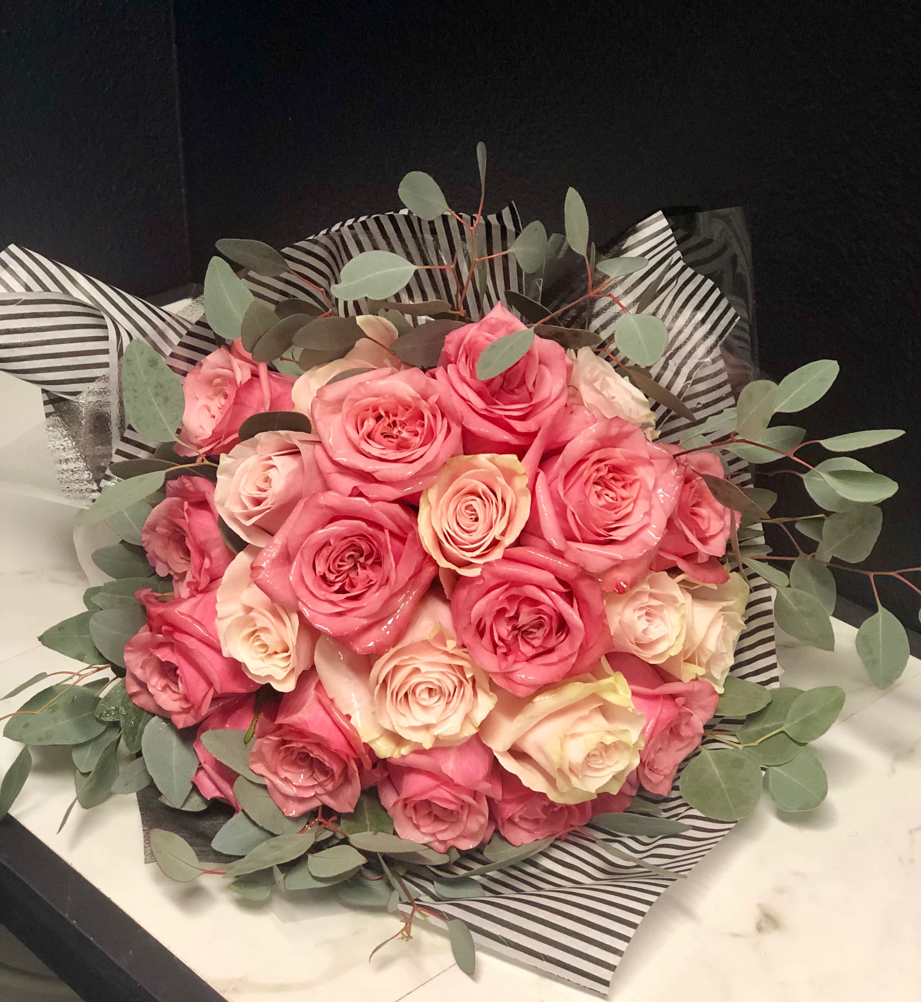 Bouquet of pink and cream roses wrapped in striped paper