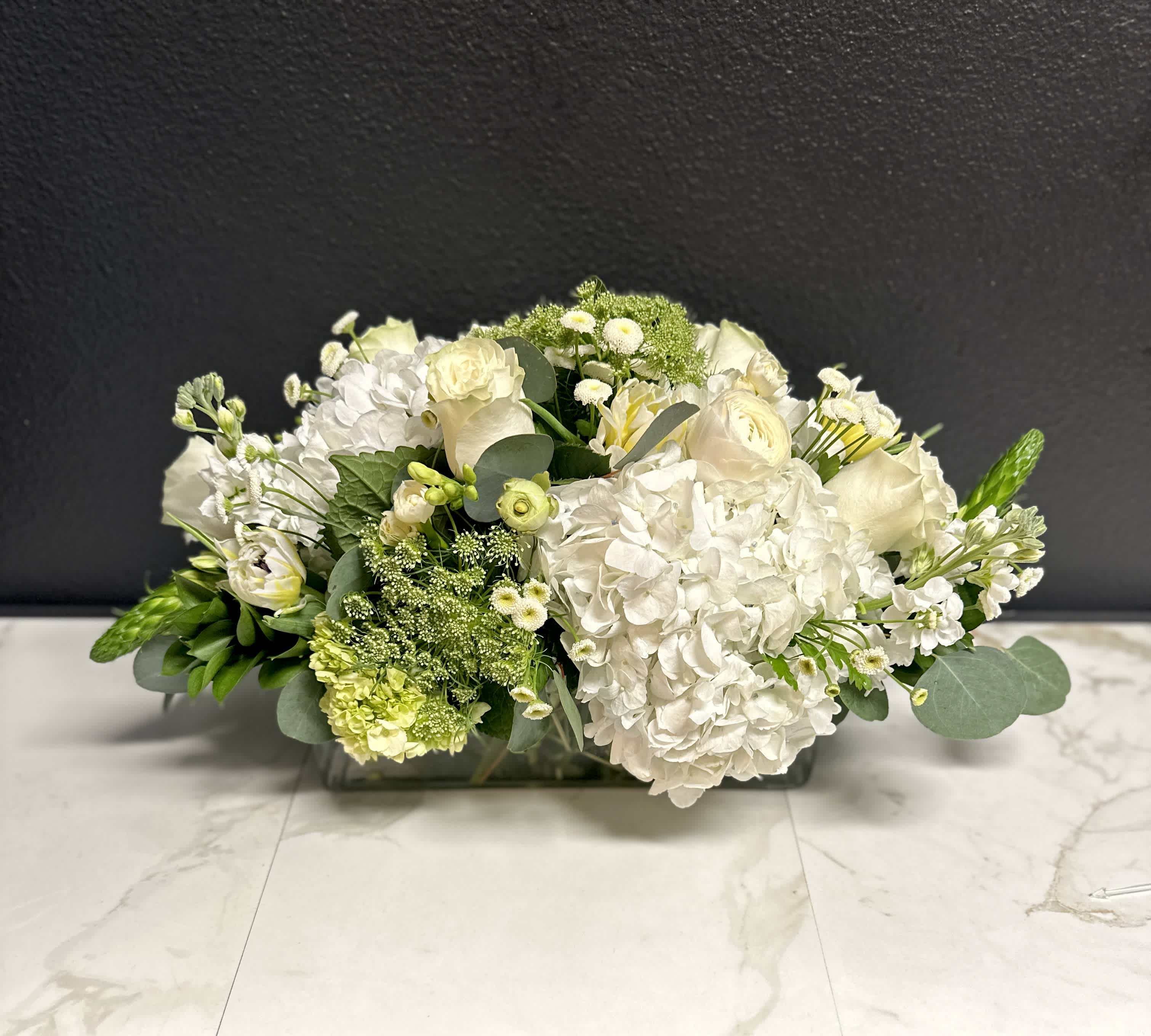 Low white floral arrangement in a rectangular glass vase