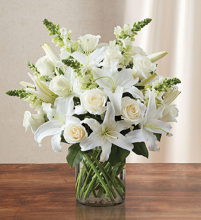 White lilies and roses arranged in a clear glass vase
