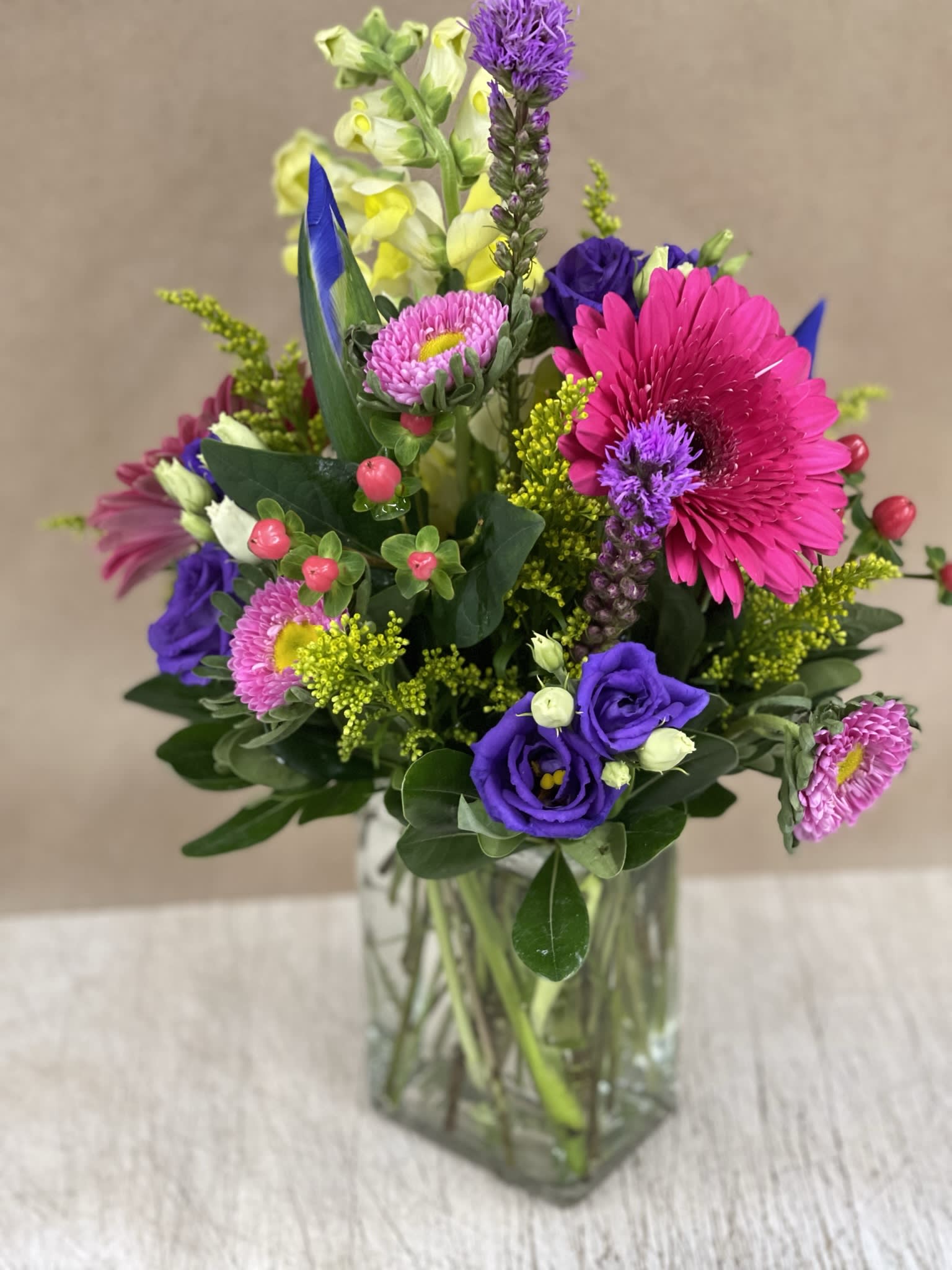 Bright mixed bouquet in a clear glass vase with pink, purple, and yellow blooms