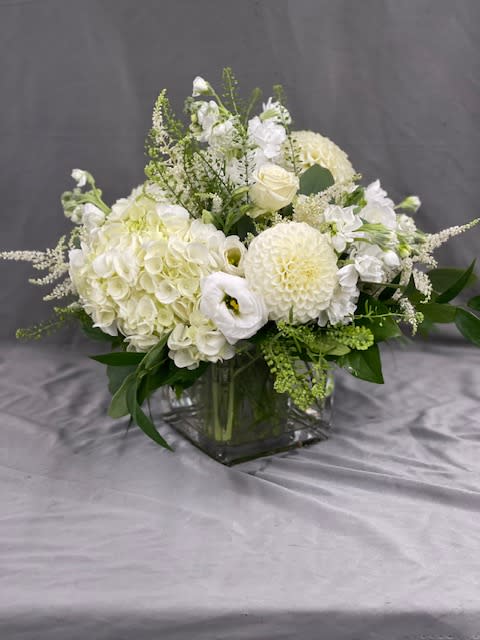 White floral arrangement in a square glass vase with round blooms