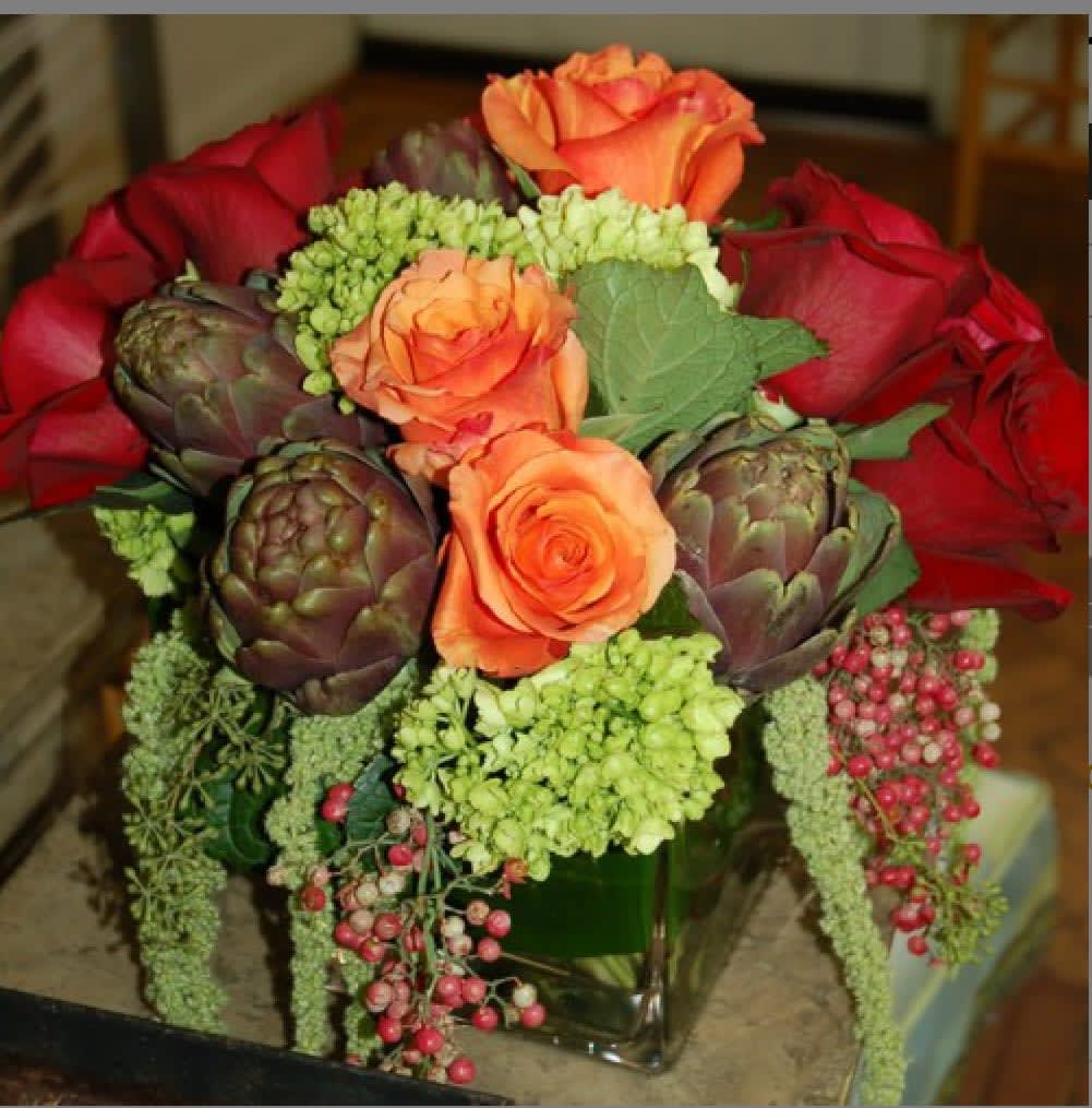 Bouquet of orange and red roses with artichokes in a glass vase
