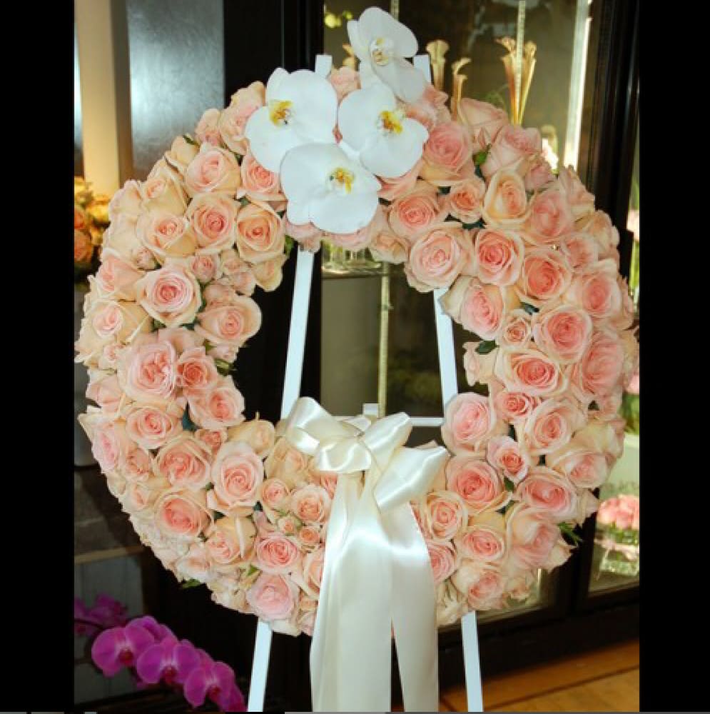Heart-shaped wreath of pale pink roses with white orchids and a satin ribbon