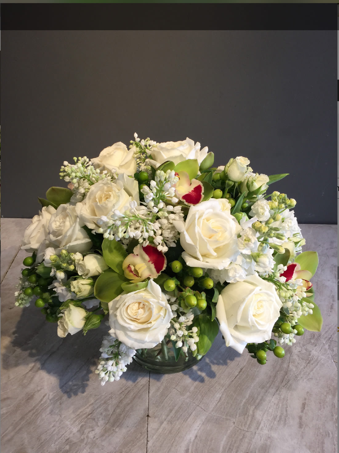 White roses and orchids arranged in a glass vase
