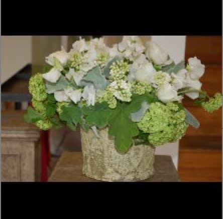White floral arrangement in a textured vase with green blooms