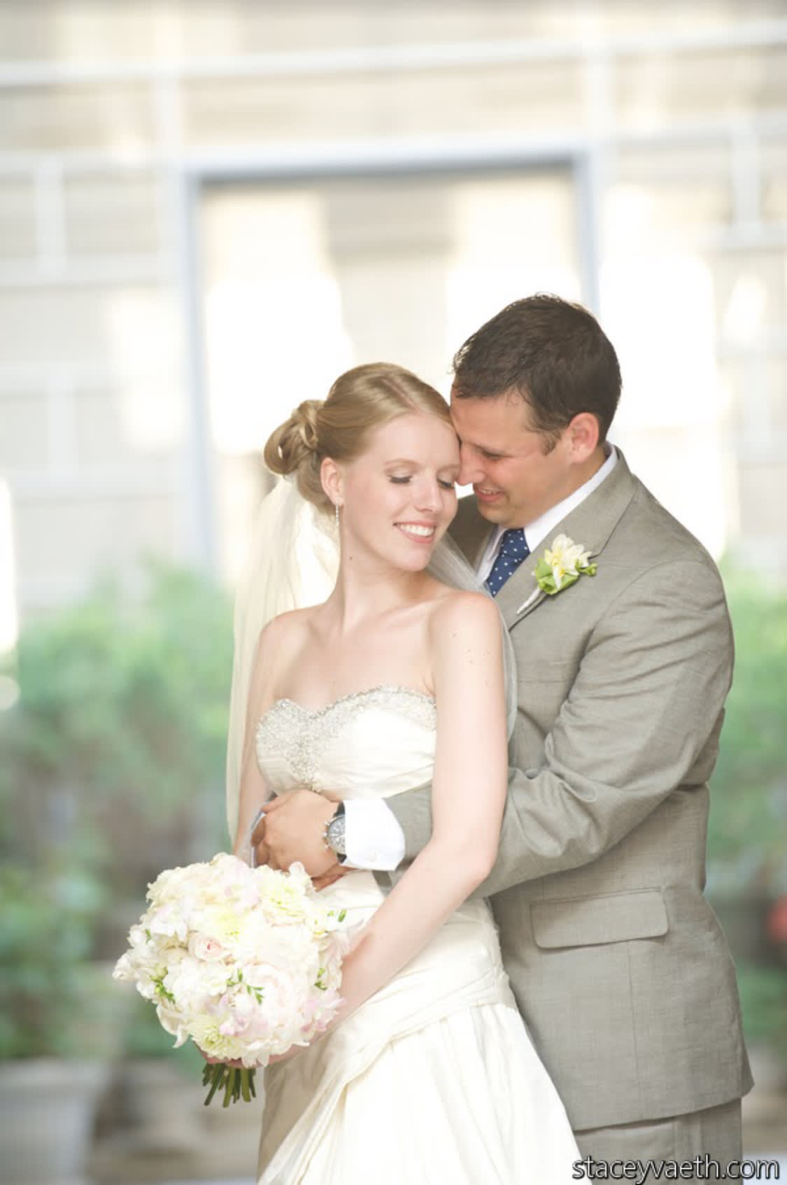 Bride holding a white and blush bouquet with groom behind her