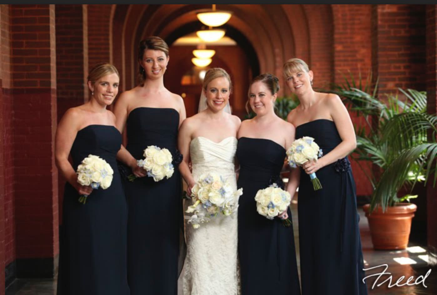 Bride and bridesmaids holding white rose bouquets