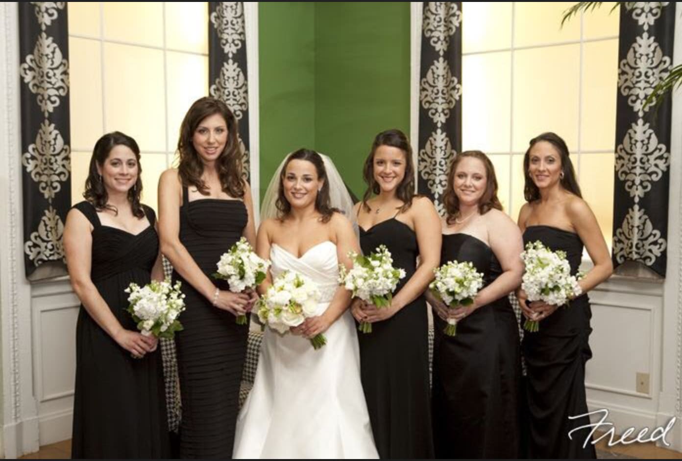 Bride and bridesmaids holding white bouquets in black dresses