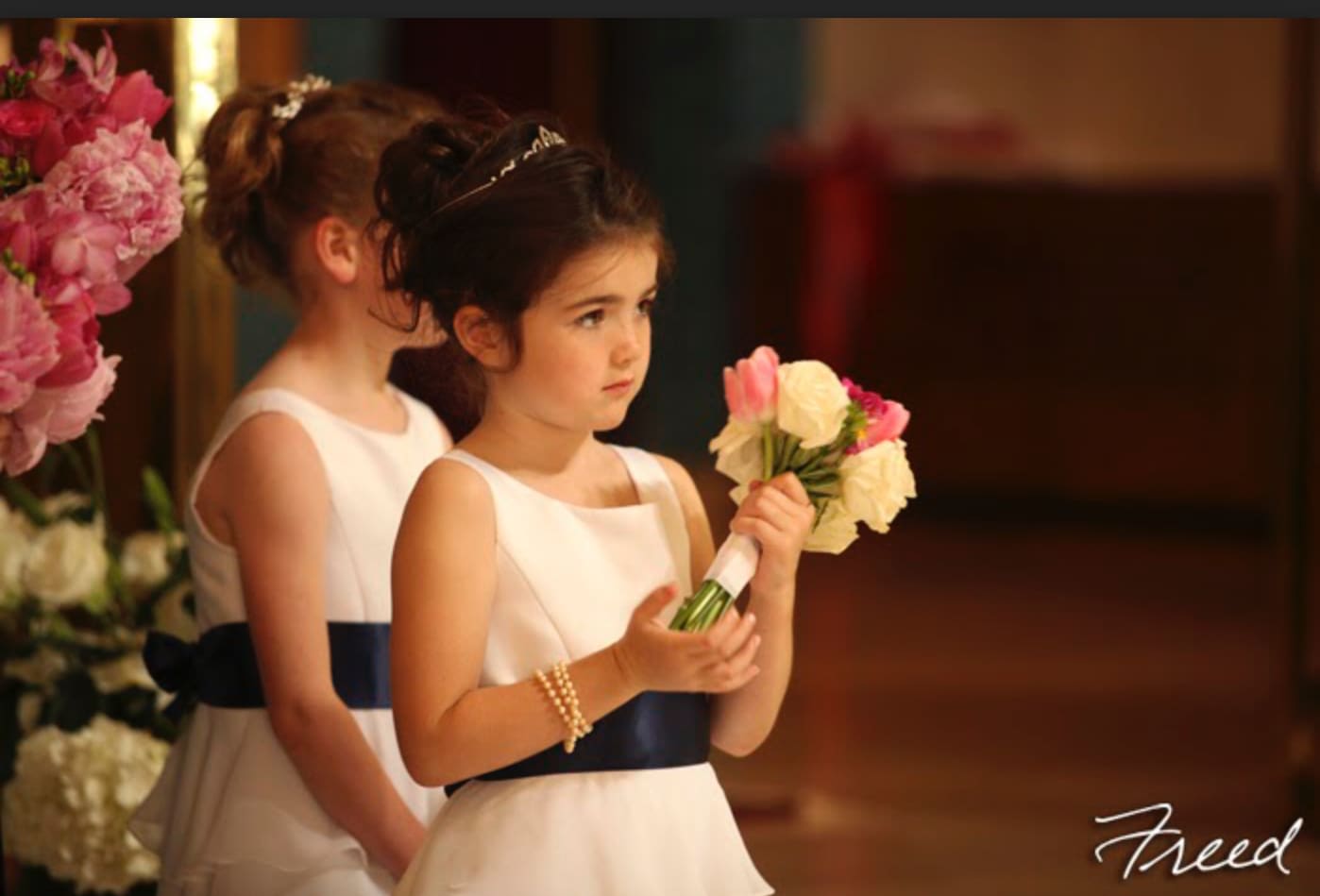 Two girls in white dresses holding small flower bouquets