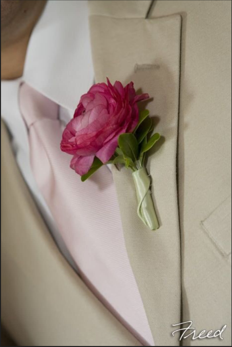 Pink boutonniere pinned to a beige suit jacket