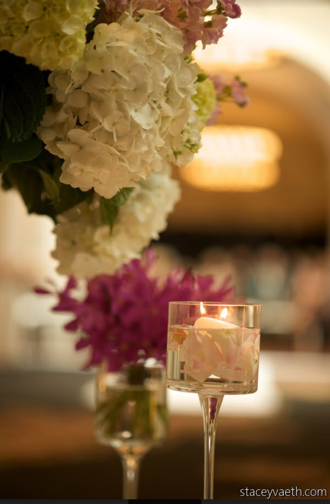 White hydrangea arrangement beside a floating candle in a glass holder