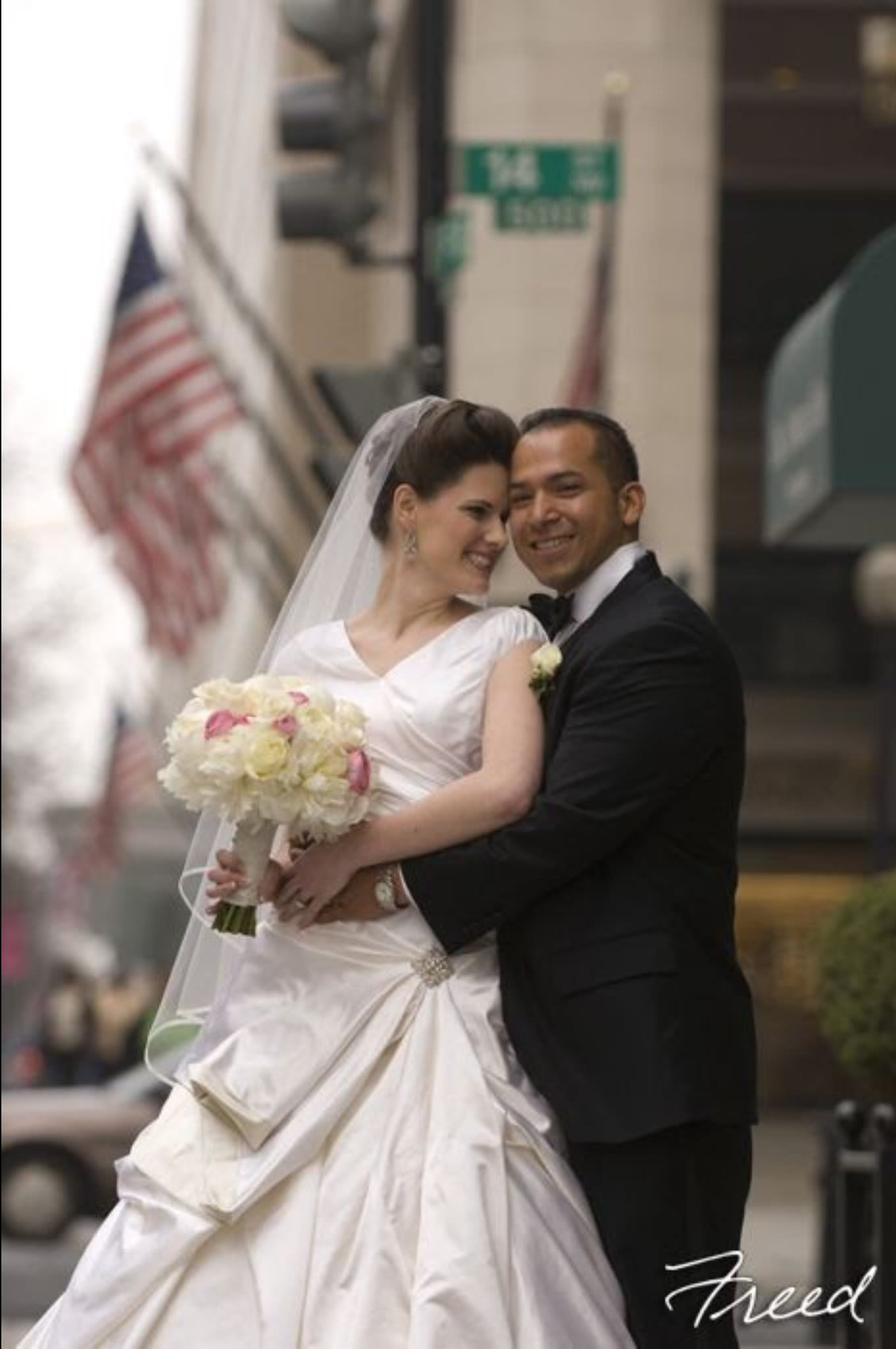 Bride and groom posing with a white and pink bouquet