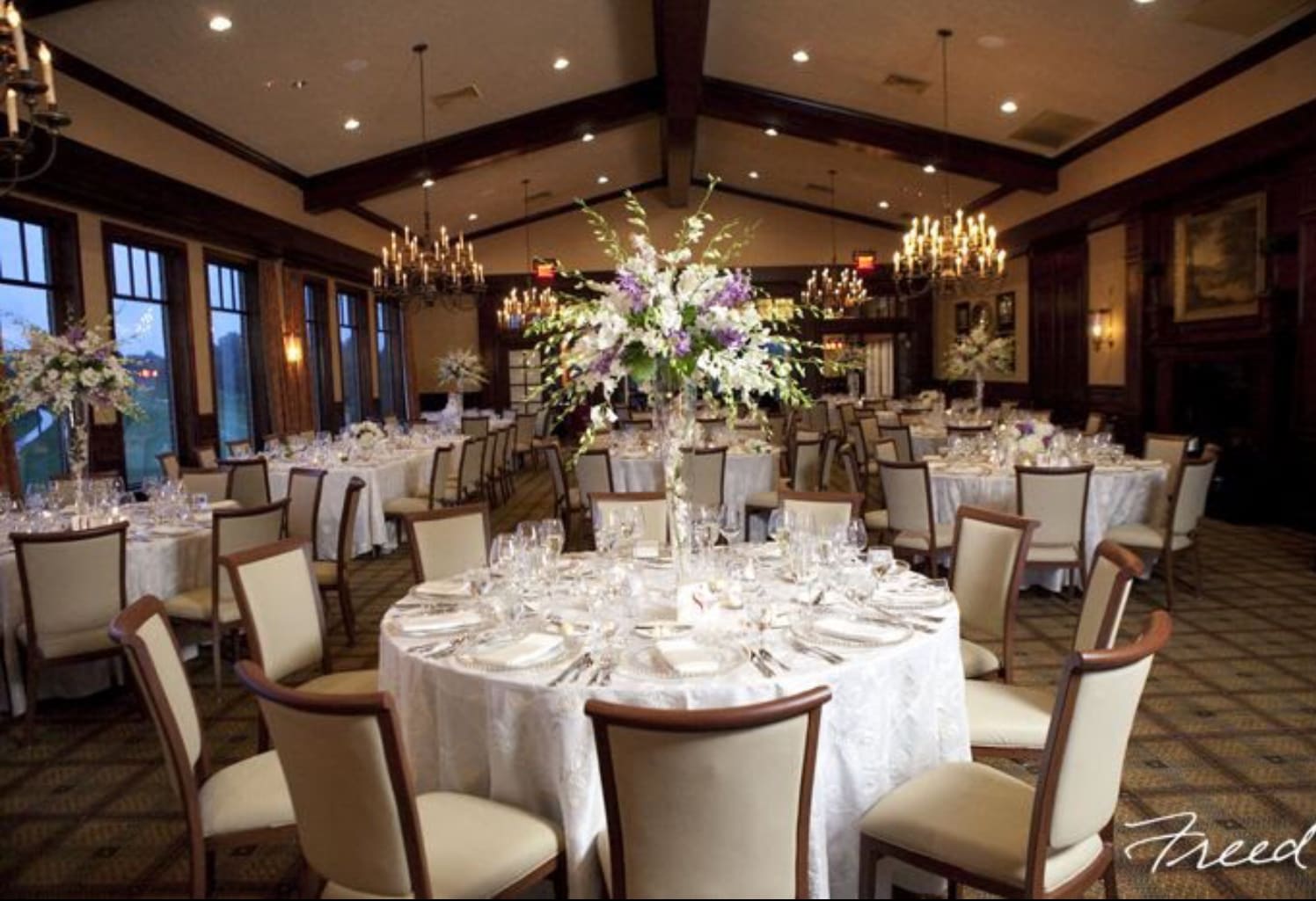 Round banquet tables with tall floral centerpieces in a formal dining room