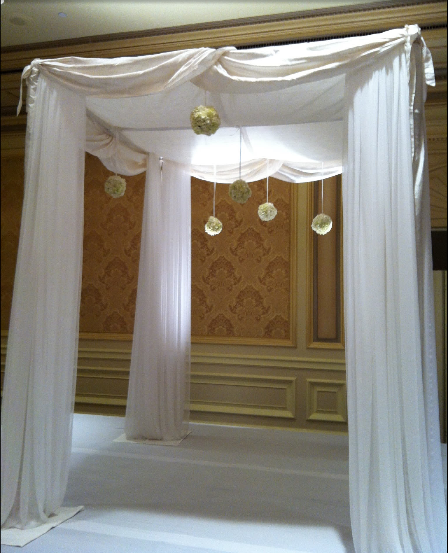 White draped wedding canopy with hanging floral pomanders