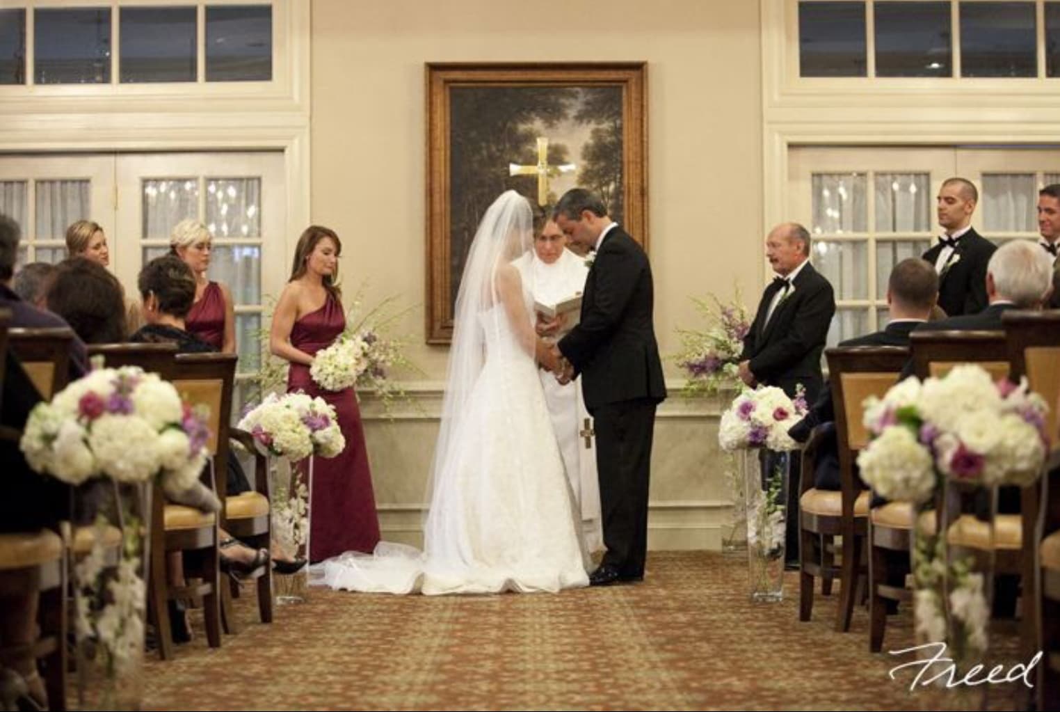 Wedding ceremony with floral aisle arrangements and bridesmaids holding bouquets
