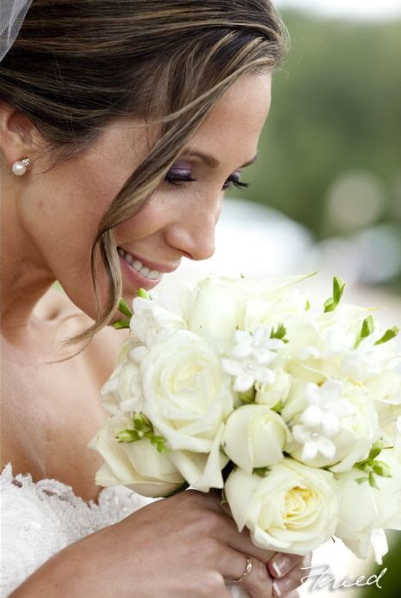 Bride holding a white bouquet of roses and small white flowers