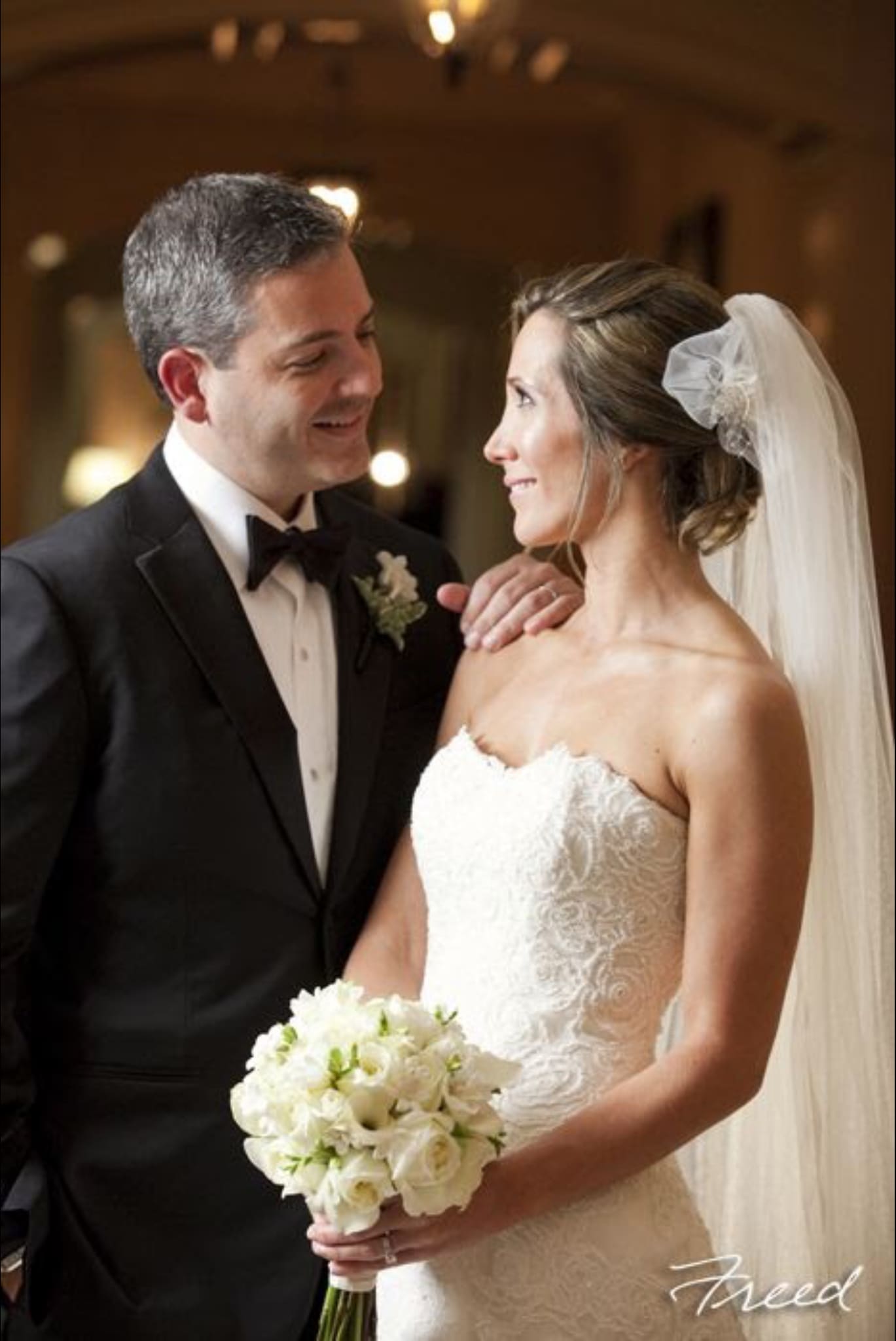 Bride holding a white bouquet beside a groom in a tuxedo