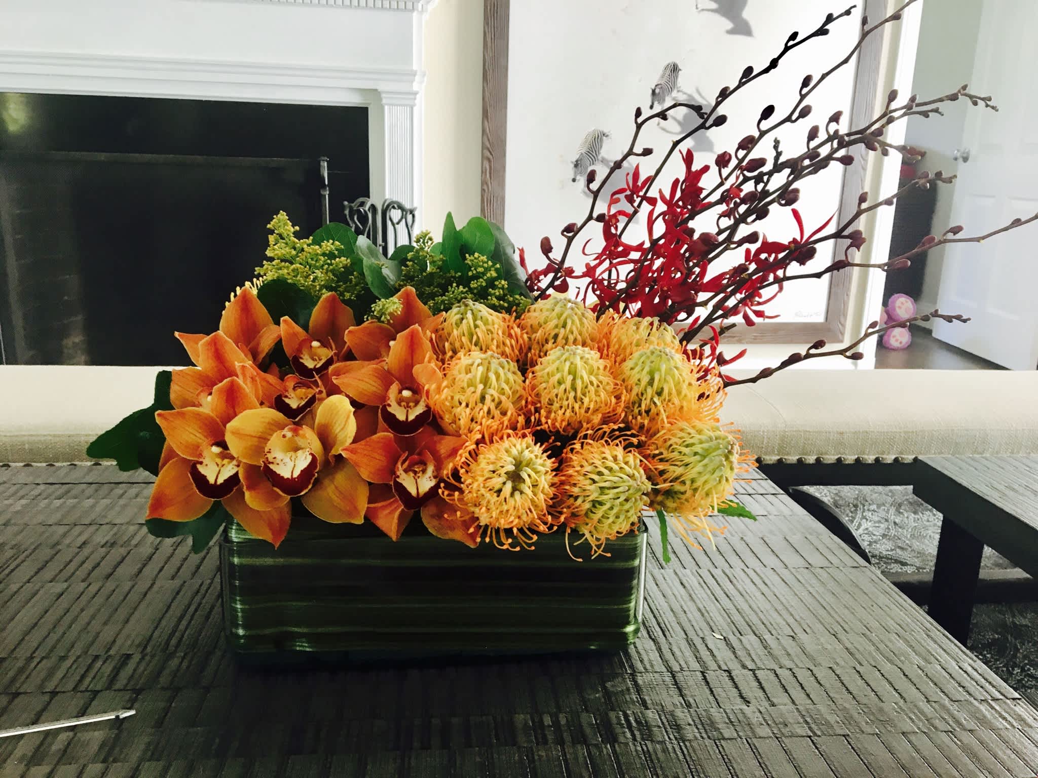 Orange orchids and yellow pincushion blooms in a rectangular vase