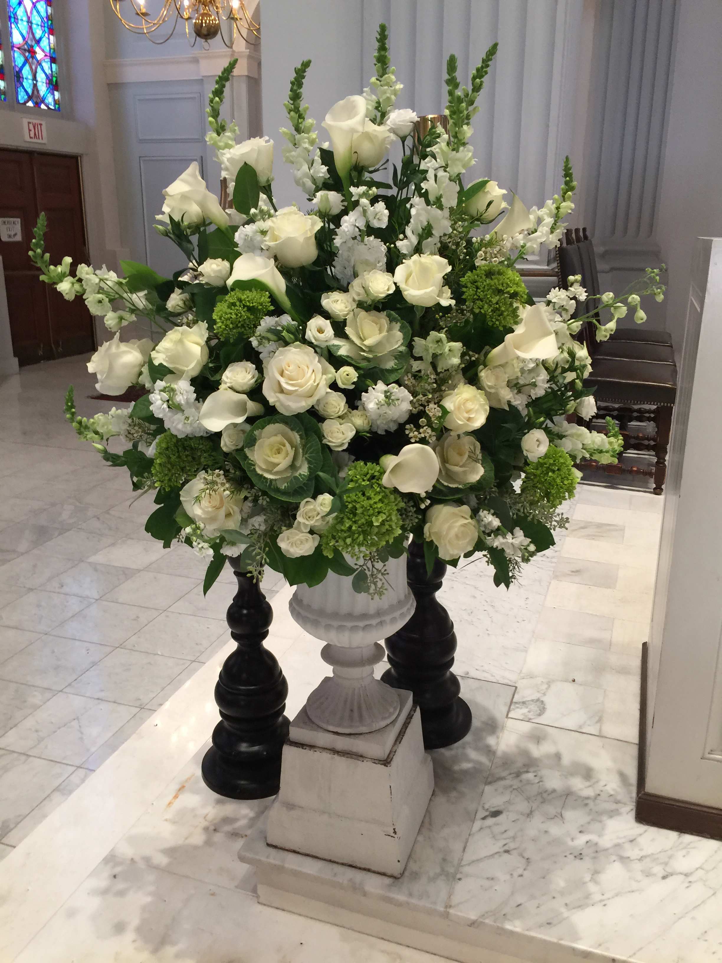 Large white floral arrangement in a pedestal urn
