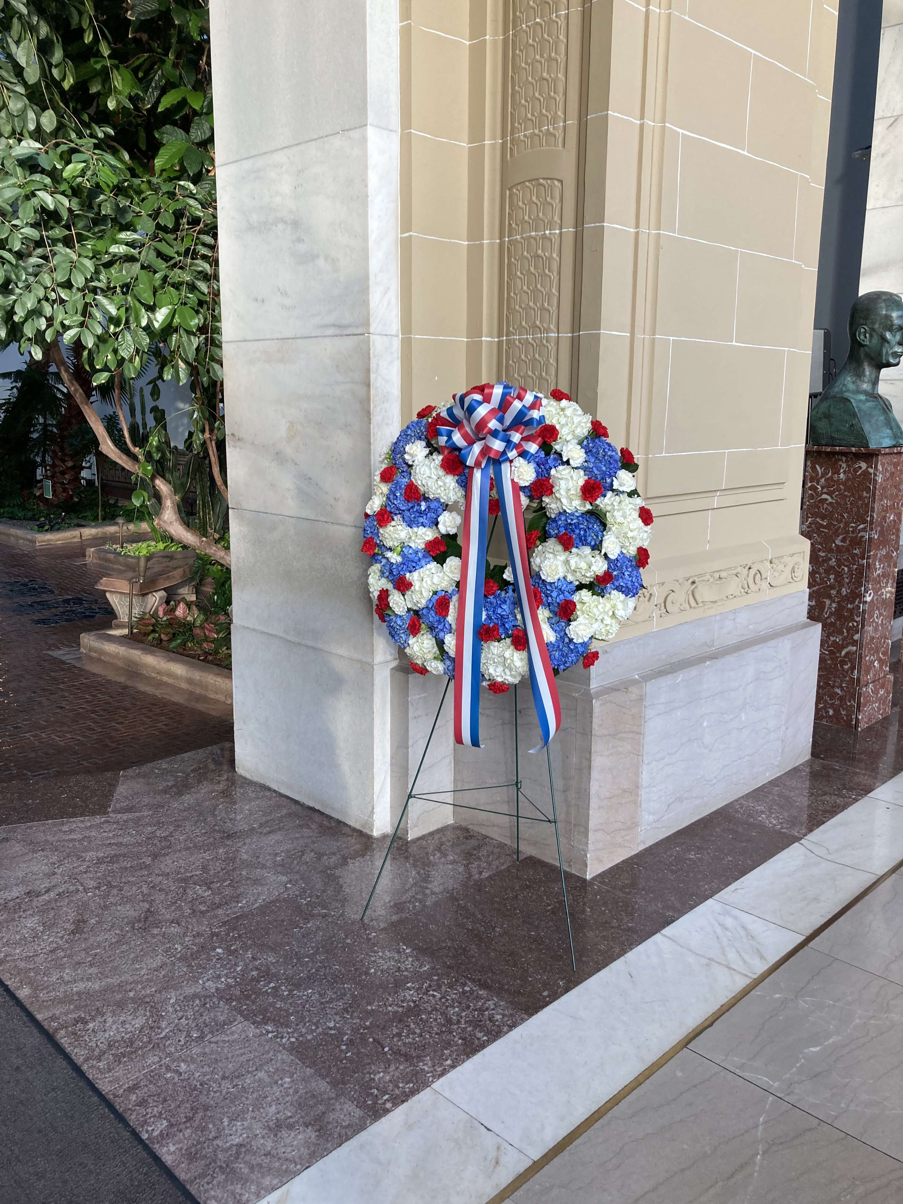 Large red, white, and blue floral wreath on a stand with ribbon