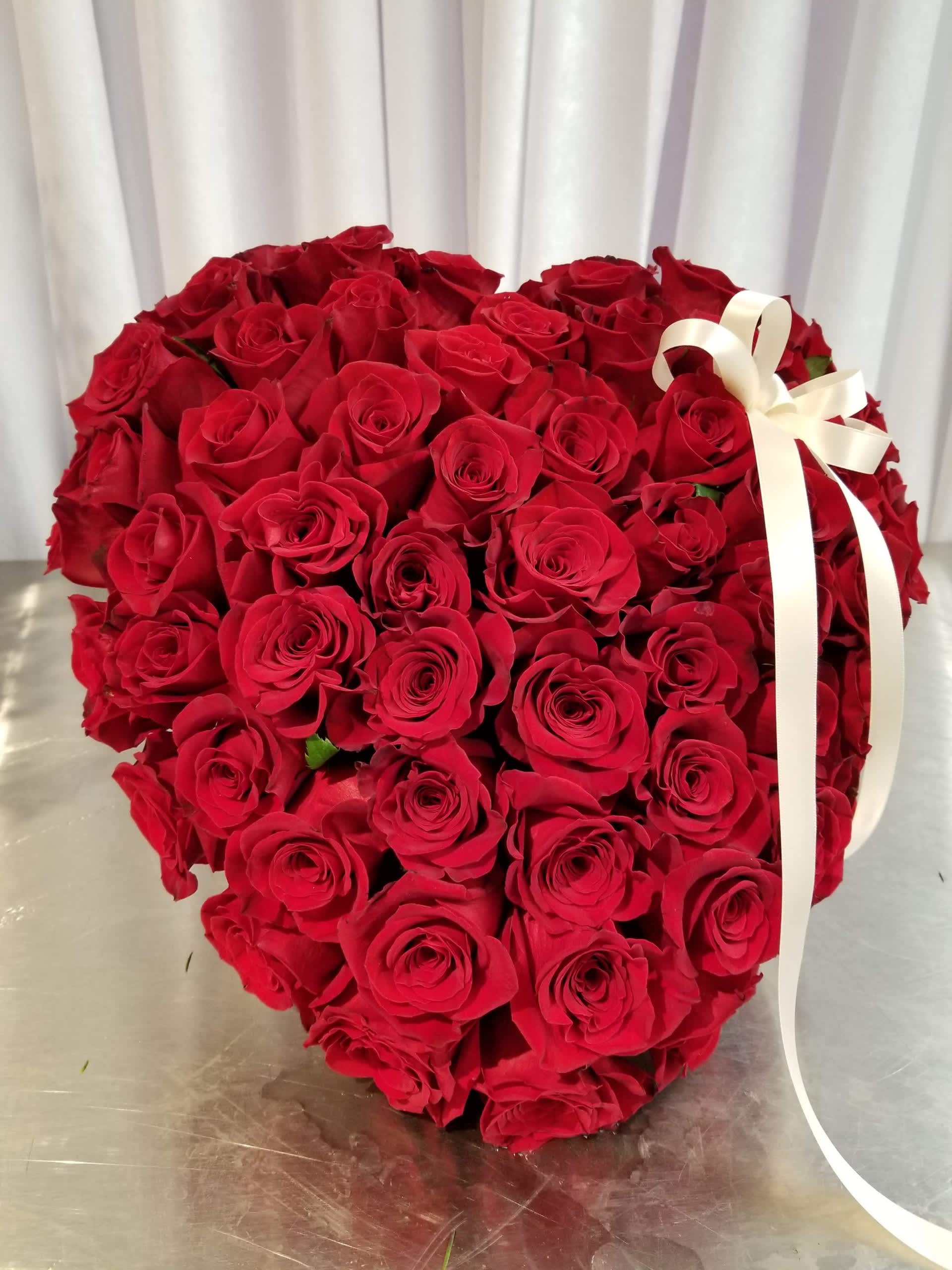 Heart-shaped bouquet of red roses with a white ribbon