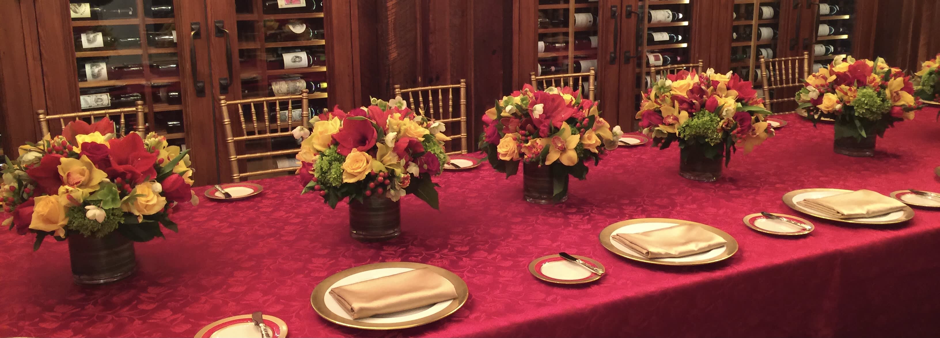 Red and yellow floral centerpieces in dark vases on a banquet table